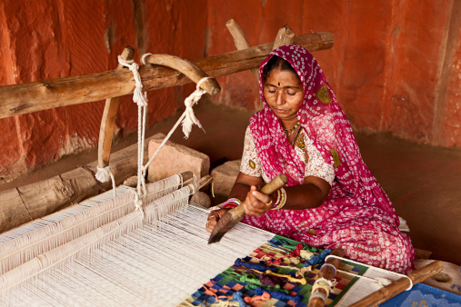 Indian man weaving durries. The durry (Rug) is weaved out of cotton or wool. The geometric designs are produced by tapestry technique which is a slow process using separate bobbins or butterflies for each colour across the width interlocking with the adjacent coloured yarn.  This old fashined form of weaving is very popular in Rajasthan, specially in Salawas village near Jodhpur.http://bem.2be.pl/IS/rajasthan_380.jpg