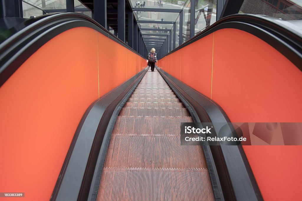 Vista posterior de mujer movimiento hacia abajo sobre rojo, escalera mecánica (XXL - Foto de stock de A la moda libre de derechos