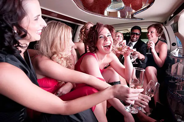 A group of well-dressed young adults party it up in an elegant limousine setting.