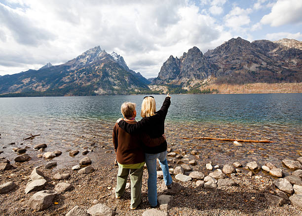 an image of a lake, river or waterfall in wyoming in late summer / early autumn/fall with tress and fantastic scenery, rocks and logs adding to the images, scenic white fluffy clouds in the blue skies