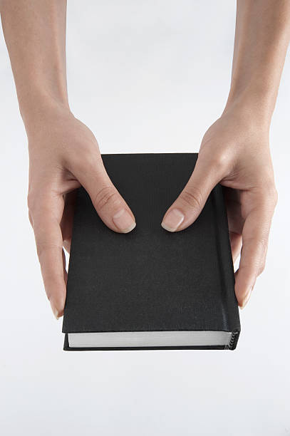istock Woman Hands Holding Black Book 183383623