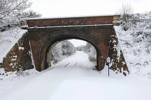 Red Brick road bridge over a snow covered railway line.