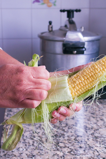 Ageless Traditions: Mature Woman Hand-Peeling Corn for Her Family's Meal.