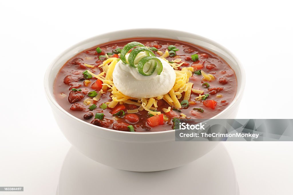 Close of up vegetarian chili in white bowl Bowl of vegetarian chili garnished with cheese, sour cream and a lime twist on clean white. Chili Pepper Stock Photo