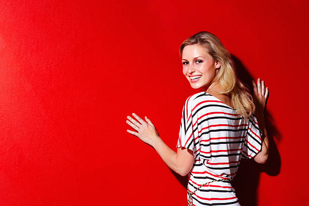 istock Smiling woman leaning against a red wall 183384990