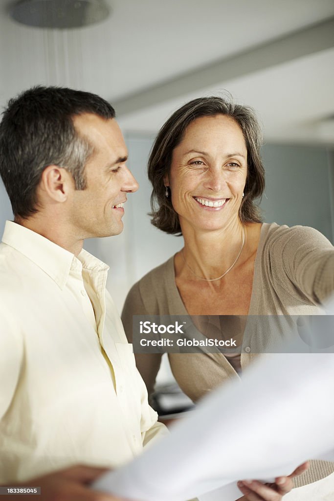 Happy, mature couple looking at blueprints of their new house "Portrait of a happy, mature couple looking at blueprints of their new house - Indoors" Mature Couple Stock Photo