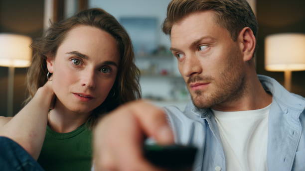 istock Relaxed pair changing tv channel indoor portrait. Man holding remote controller 1833863238