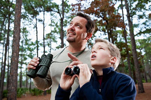 Two men, a young adult and a mature adult, watching birds and nature in a wetland, enjoying outdoor hobby