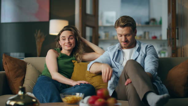 istock Relaxed partners chilling sofa watching tv evening. Smiling man turning channels 1833868892