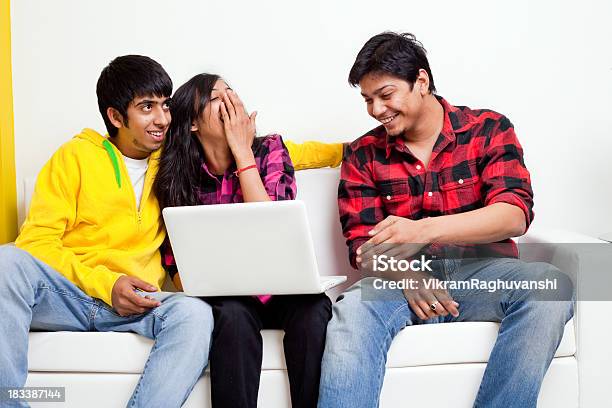 Three Young Indian Alegre Amigos Con Una Computadora Portátil En El Sofá De La Sala De Estar Con Sofá Foto de stock y más banco de imágenes de 20 a 29 años