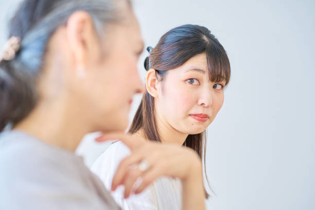 A young woman feels stressed next to a senior woman A young woman feels stressed next to a senior woman in the room annoying mother in law stock pictures, royalty-free photos & images