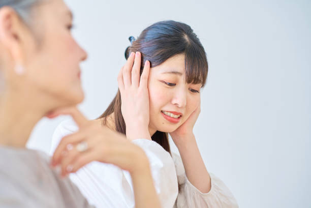 A young woman feels stressed next to a senior woman A young woman feels stressed next to a senior woman in the room annoying mother in law stock pictures, royalty-free photos & images
