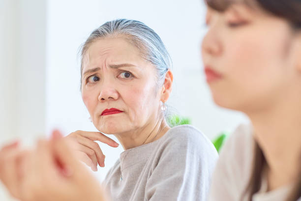 A senior woman looking at a young woman with a grim expression A senior woman looking at a young woman with a grim expression in the room annoying mother in law stock pictures, royalty-free photos & images
