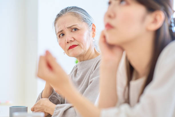 A senior woman looking at a young woman with a grim expression A senior woman looking at a young woman with a grim expression in the room annoying mother in law stock pictures, royalty-free photos & images