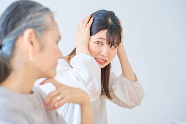A young woman feels stressed next to a senior woman A young woman feels stressed next to a senior woman in the room annoying mother in law stock pictures, royalty-free photos & images