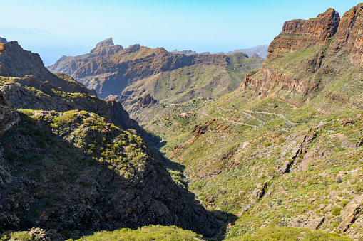 View from the Mirador de Masca showing the twisting narrow road to Masca, TF-436, and the hilltop remote village of Masca in the Teno mountains of the Canary island of Tenerife Spain.
