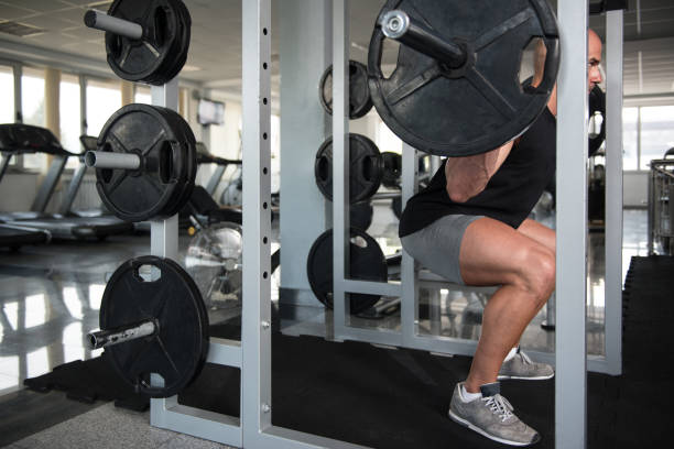 istock Fitness Man Using Barbell Exercising Legs Inside Gym 1833957668