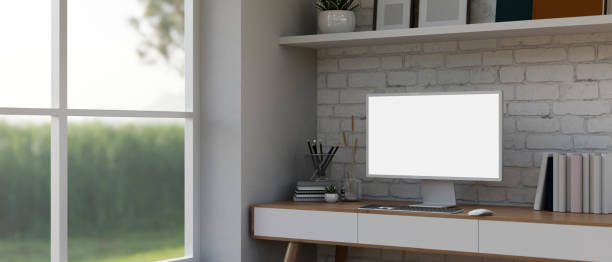 istock Modern white home office with an empty computer monitor mockup on a desk against a white brick wall. 1834012728