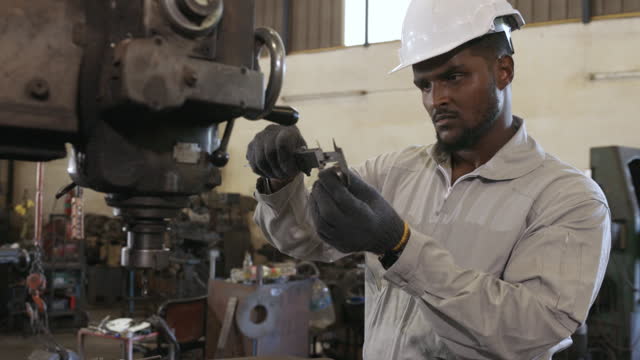 Black man engineer measuring workpiece in factory