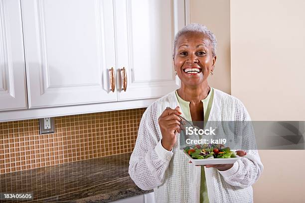 Foto de Madura Afroamericana Mulher Comendo Salada Na Cozinha e mais fotos de stock de Terceira idade