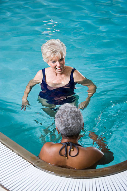 multiraciale femmes âgées discuter de la piscine - sc0450 photos et images de collection