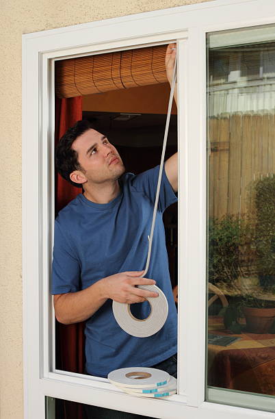 Man Installs Weather Stripping in Window Energy saving here I come. undressing stock pictures, royalty-free photos & images