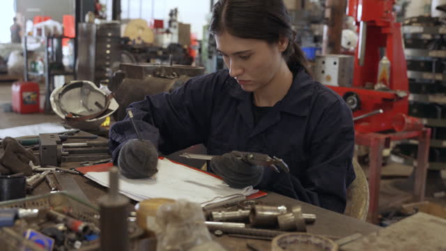 Female engineer measuring workpiece in factory
