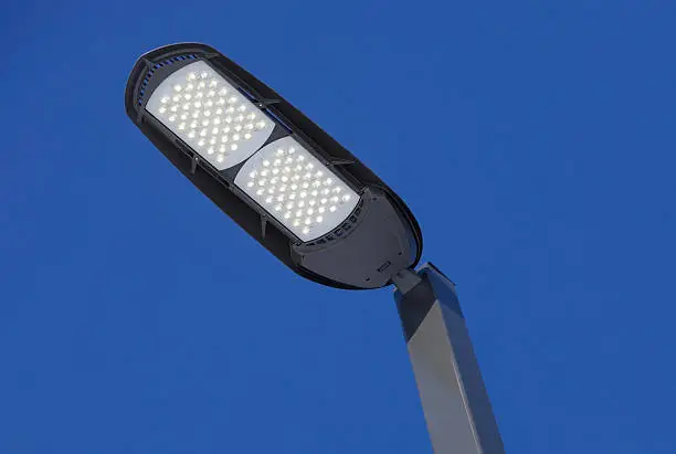 "A new, illuminated, LED streetlight against a clear blue sky at dusk. LEDs represent the latest in lighting technology, although initially more expensive than traditional lights, LEDs are being considered for energy efficient installations around the world.Related images from my portfolio:"