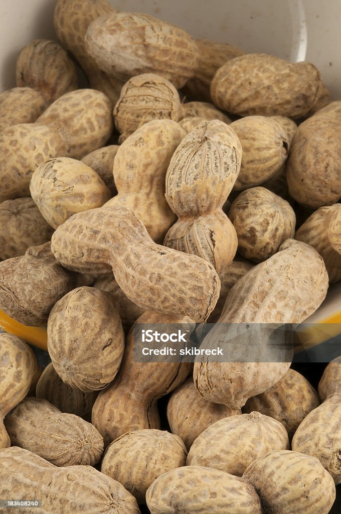 Roasted and Salted Peanuts Falling from a Bowl "Roasted and salted peanuts, still in the shell, falling from a bowl." Bowl Stock Photo