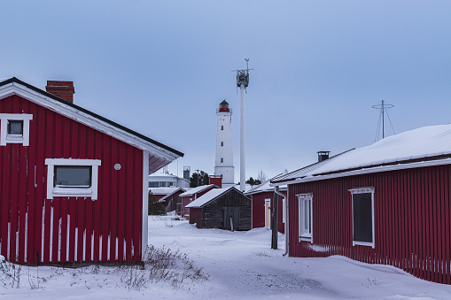 red, old houses on the background of a winter lighthouse, Hailuoto in Hailuoto, North Ostrobothnia, Finland