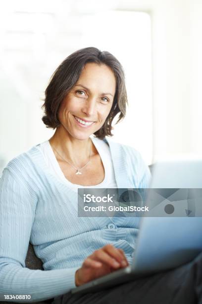 Sorridente Mulher Madura Sentado Com Um Computador Portátil - Fotografias de stock e mais imagens de 40-49 Anos