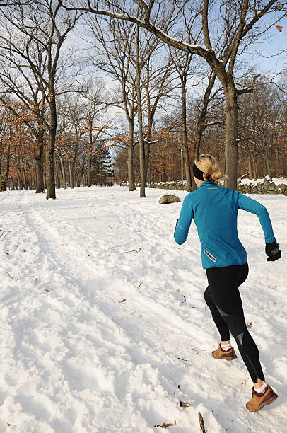 Woman runner on snow covered trail stock photo