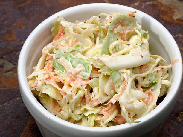 White ramekin of coleslaw on stone counter Creamy Cabbage and Carrot Coleslaw Salad in white ramekin on rustic tile coleslaw stock pictures, royalty-free photos & images