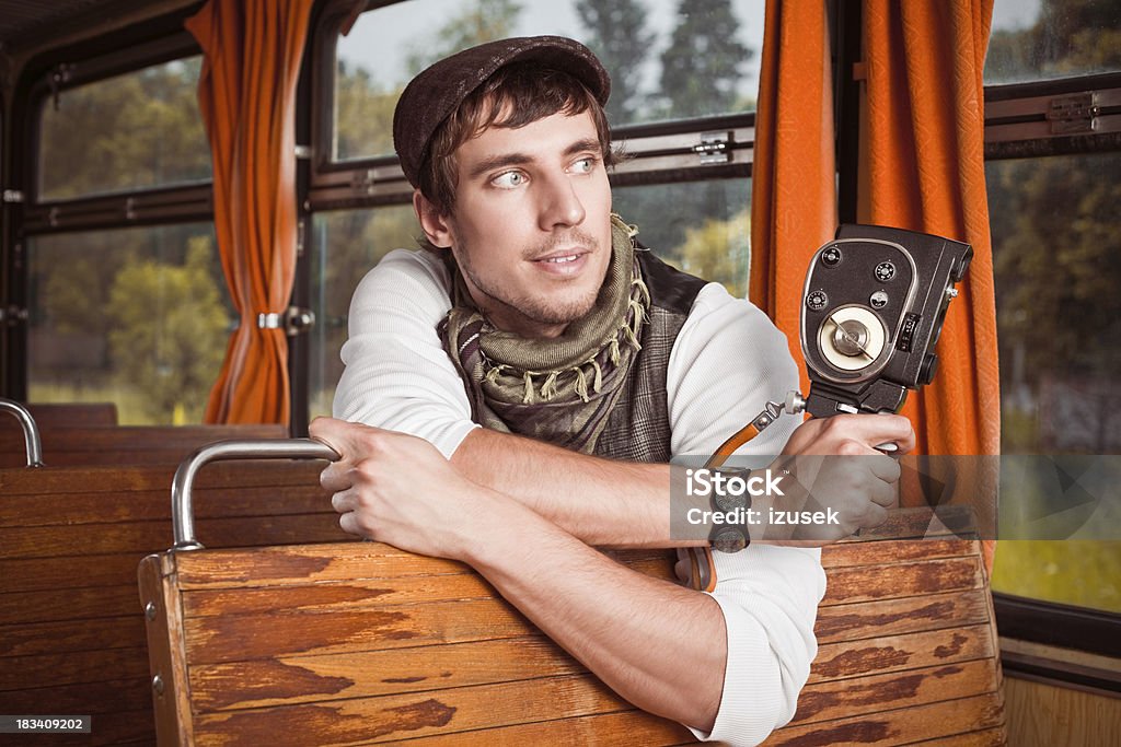 Young adult man with vintage camera "An attractive, smiling young adult man sitting in the old school train and holding the vintage camera in her hands." 20-24 Years Stock Photo