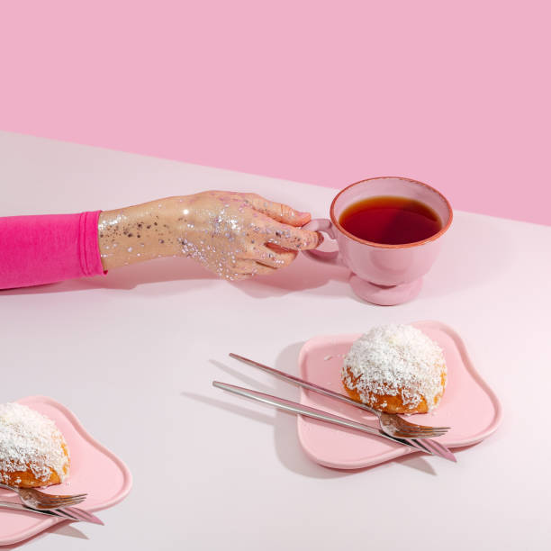 istock a woman's hand holds a pink cup of tea next to a plate with a bun 1834096258