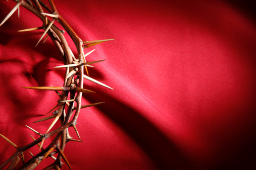 A crown of thorns on a red cloth background.