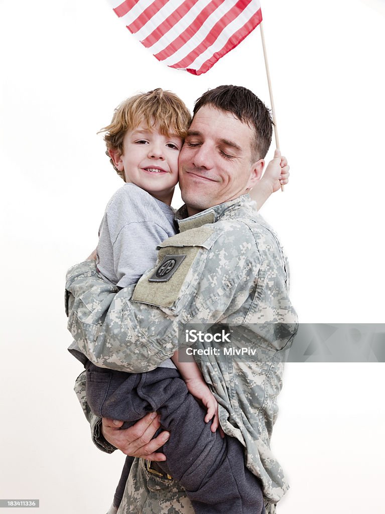 American soldier with his son A 5 year old boy hugging his soldier dad and holding an American flag Adult Stock Photo