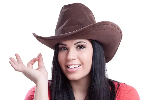 Attractive young woman wearing a cowboy hat and giving the okay hand sign.