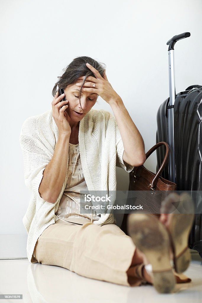 Cansado mulher madura espera por um voo atrasado - Foto de stock de Adulto royalty-free