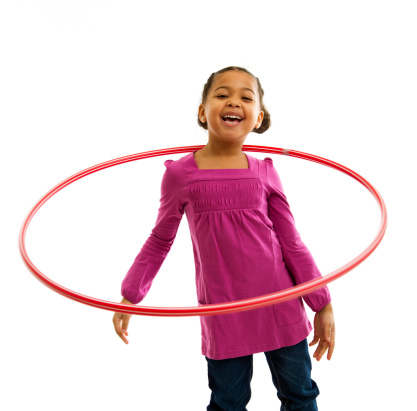 6 year old child playing with a hulahoop isolated on white background.