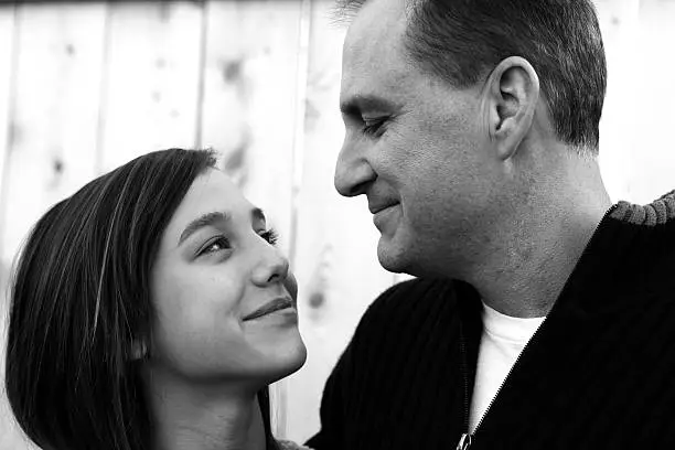Photo of Father and Daughter Smiling at Each Other