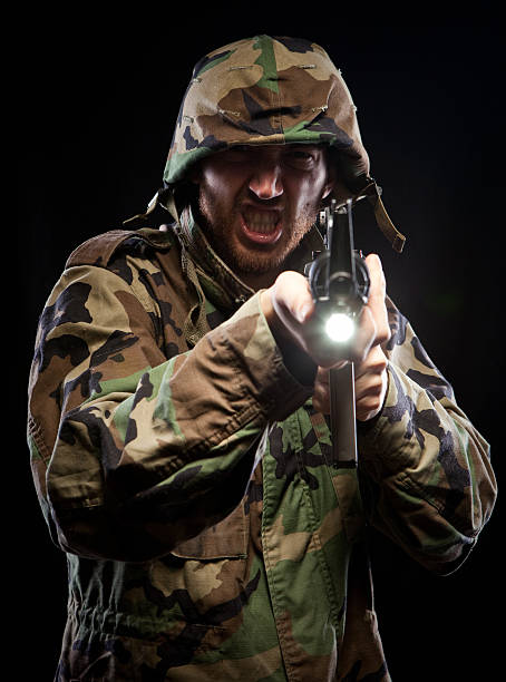 Armed military man firing machine gun in camoflage US Army man with m16 in the heat of an urban battle.  He is ready for his call of duty and is in action! Green vietnam era camouflage with helmet. special forces vietnam stock pictures, royalty-free photos & images