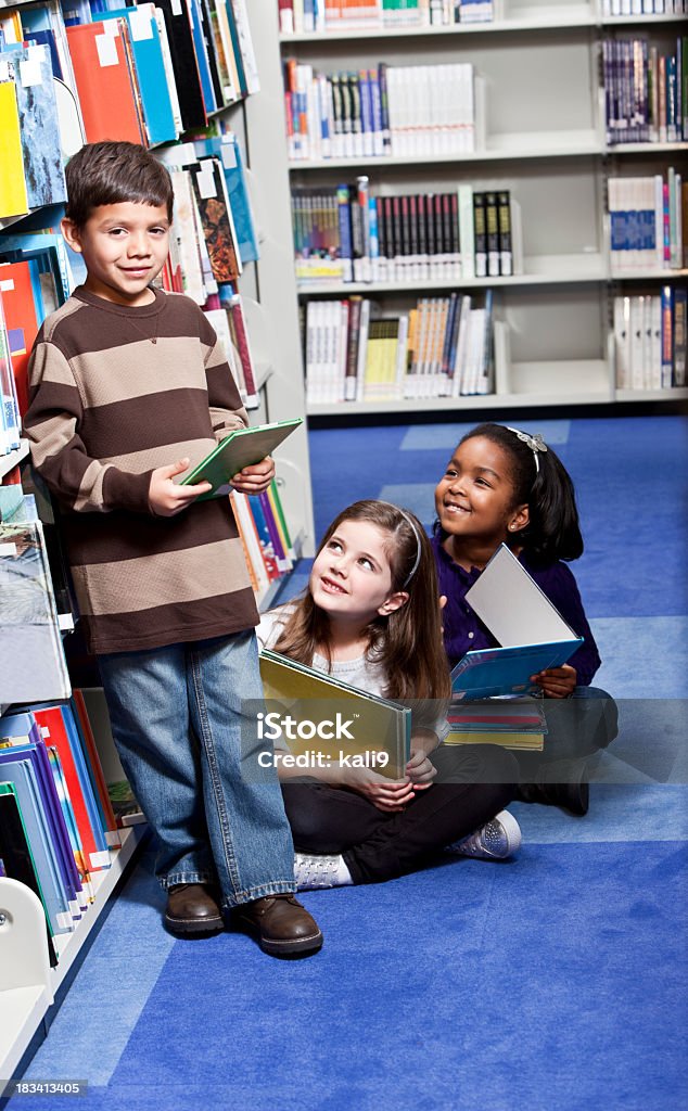 Gruppo eterogeneo di giovani figli nella Libreria - Foto stock royalty-free di 6-7 anni