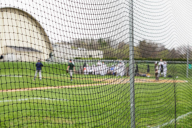 jugadores de béisbol detrás de red de seguridad en high school los deportes - baseball diamond baseball baseline grass fotografías e imágenes de stock