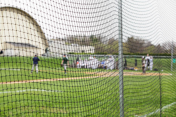 joueurs de baseball de filet de sécurité à l'école match - baseball diamond baseball baseline grass photos et images de collection