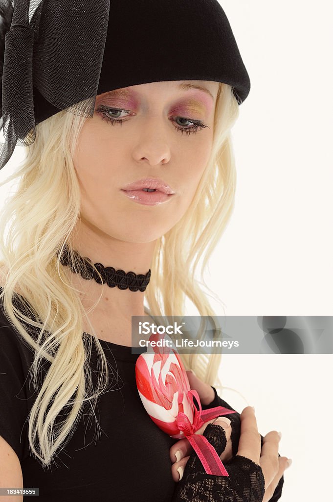 Pretty Woman In Black Hat & Chocker Holding Heart Sucker Pretty Woman In Black Hat & Choker Holding A Pink and White Stripped Heart Sucker.  In Studio shot.  A little glamour. A little fun.  Copy Space. 20-24 Years Stock Photo