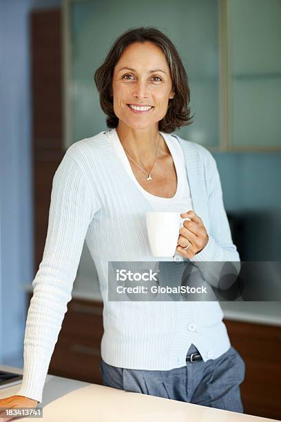 Tranquila Mujer Sosteniendo Una Taza De Café En La Cocina Foto de stock y más banco de imágenes de 40-49 años