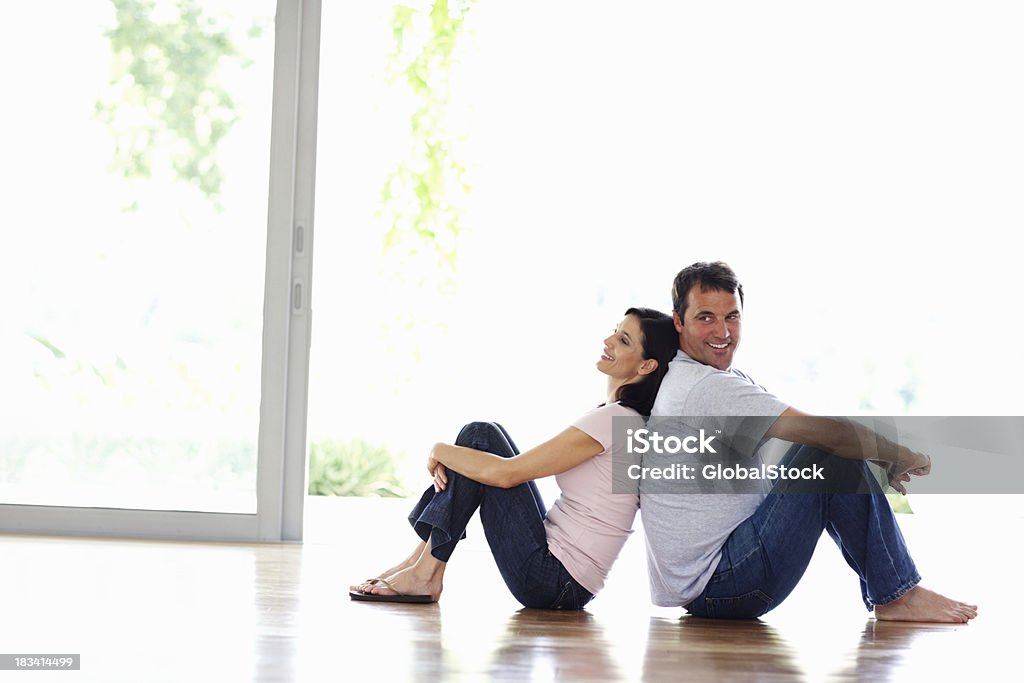 Couple heureux se détendre à la maison - Photo de Assis par terre libre de droits