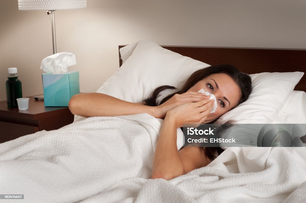 Kranke Frau im Bett Schnäuzen - Lizenzfrei Bett Stock-Foto