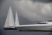 Luxury yacht and sailboats before a cloudy sky